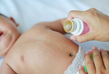 Mother applying vanishing medicine for infant to prevent stomachache. Baby have a stomach ache.の写真素材
