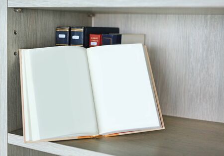 Open blank hardcover book on bookshelf in library.の写真素材