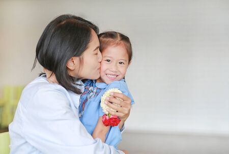 Portrait of Asian mom kissing and hugging her daughter on Mother's day in thailand. Little child girl Pay respect and give Thai traditional jasmine garland to mother.の写真素材