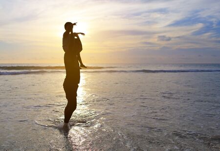 Silhouette father were riding neck carries daughter look out at the sea at sunset.の写真素材