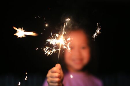 Close up little Asian girl holding fire sparklers.の写真素材