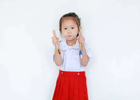 Portrait of asian child in school uniform holding color pencil isolated on white background.の写真素材