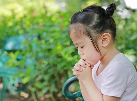 Little child girl praying in the gardenの写真素材