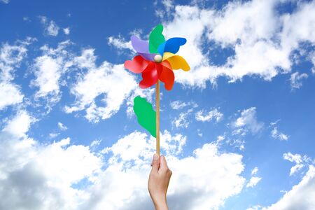 Hand holding pinwheel against skyの写真素材