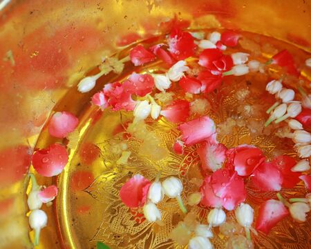 Holy water mixed and flower petals with perfume in a golden bowl by monk in Buddhist merit of Thai. For Blessing or Holy water in Culture Thailand.の写真素材