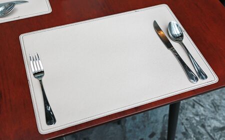 Empty fork and spoon set on leather against wooden tableの写真素材