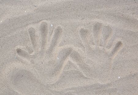 Hands stamp on the sand background.