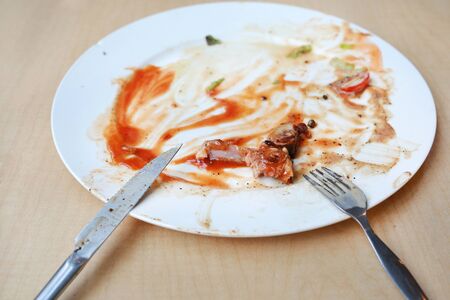 Dirty dish of spicy spaghetti after eaten with spoon and fork.