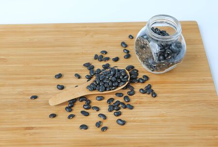 Black eyed peas beans in bottle and wooden spoon on bamboo wooden board