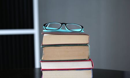 Stack of hardback books with glasses on wooden table. Education background.の写真素材