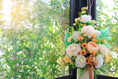 Beautiful artificial flowers in white ceramic vase decoration in living room near a window glass.の写真素材