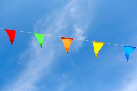 Colorful Flags in Thai temple fair against blue sky background.