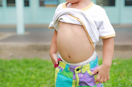 Close up little boy lifting his shirt show exposing his big tummy.の写真素材