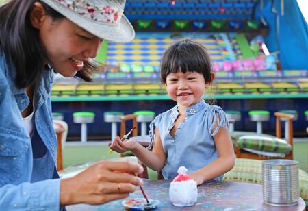 Asian Mother and her daughter having fun to paint on stucco dollの写真素材