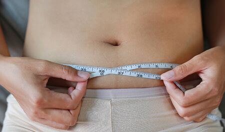 Close-up woman body fat overweight. measure tape or line tape.の写真素材