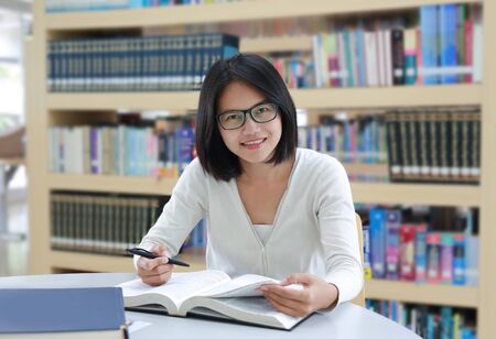 Asian student reading book in the library at universityの写真素材