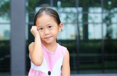Cute Asian child girl posture her hand on head with little smile.の写真素材