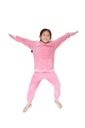 Funny little Asian child girl in pink tracksuit or sport cloth jumping on air over white background. Freedom kid movement concept.の写真素材