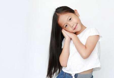 Beautiful caucasian little child girl sleep gesture posing with hands together while smiling with looking at camera isolated over white background.の写真素材