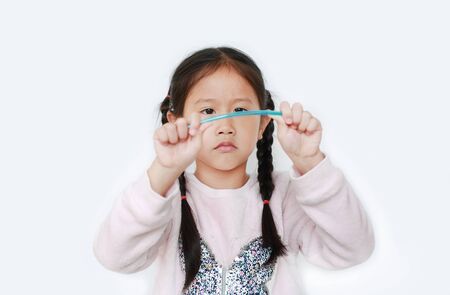 Child girl is breaking plastic wood isolated on white background.の写真素材