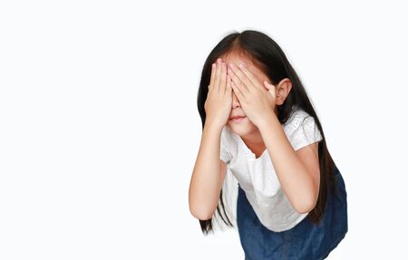 Little caucasian kid girl closing hid eyes by hand isolated on white background with copy space. Kid is crying and rubbing her eyes with her hands.の写真素材