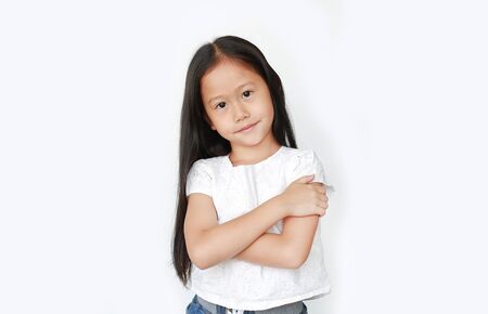 Smiling little Asian child girl expression cross one's arm and looking camera isolated on white background. Confident and cheerful kids concept.の写真素材