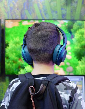 Rear of boy gamer with headphones playing competitive gaming.