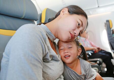 Happy mother and her daughter on the seat of airplane.の写真素材