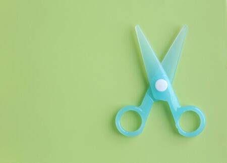 Cyan Plastic children safety scissors on green background.の写真素材