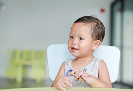 Happy little Asian baby boy eating chocolate in the classroom.の写真素材