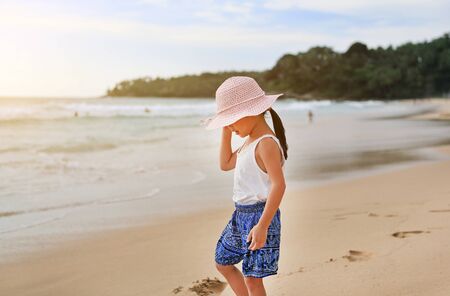 Cute little asian girl wear straw hat walking on the beachの写真素材