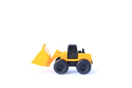 The yellow toy car Bulldozer isolated on white background. Children's tractor toy. Wheel loader...