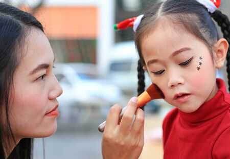 Close up Asian mother applying makeup on her daughter face.の写真素材