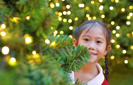 Close-up Asian little girl in winter season and happy new year festival against christmas tree background.の写真素材