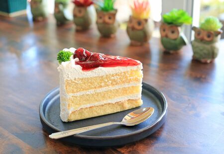 Strawberry cake in metal tray with spoon on wooden table at cafe.の写真素材