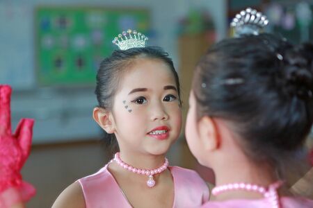 Close up little ballerina girl in a pink tutu posing with mirror reflection and looking at camera.の写真素材
