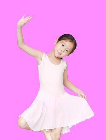 Happy Asian ballet dancer girl in pink tutu skirt isolated on purple background.の写真素材