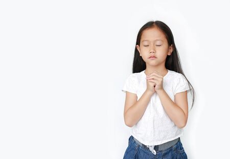 Close eyes beautiful little asian child girl praying isolated on white background with copy space. Spirituality and religion concept.の写真素材