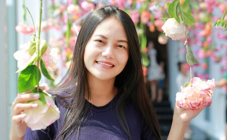 Beautiful young Asian woman posing near pink flowers in a garden.