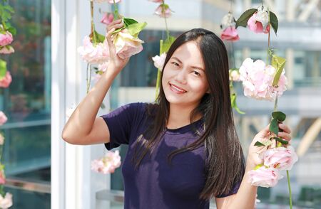 Beautiful young Asian woman posing near pink flowers in a garden.