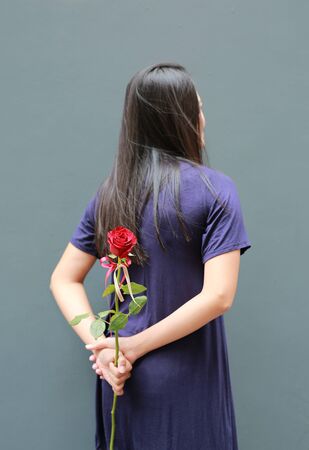 Portrait of Asian woman hiding red roses behind her back. Rear view.の写真素材