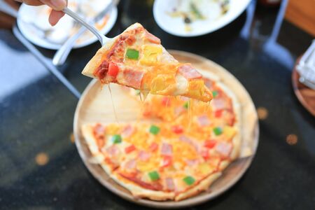 Delicious Hawaiian Pizza served on wood tray against on black table.の写真素材