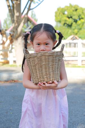 Adorable little asian girl holding a basket outdoors in the farms.の写真素材