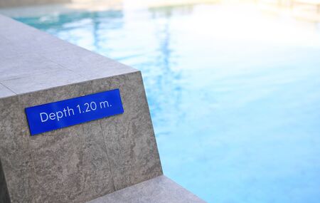 Edge of swimming pool and sign indicating the depth 1.20 meter of the pool.の写真素材