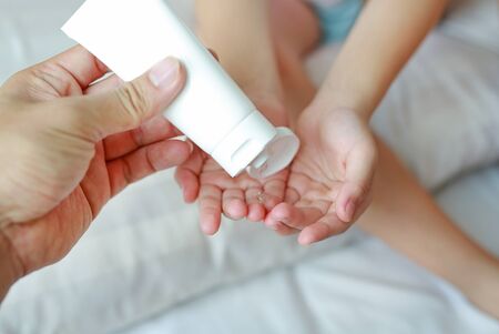 Mother hand applying alcohol gel from plastic bottle for cleaning baby hands for hygiene and anti virus bacteria.の写真素材