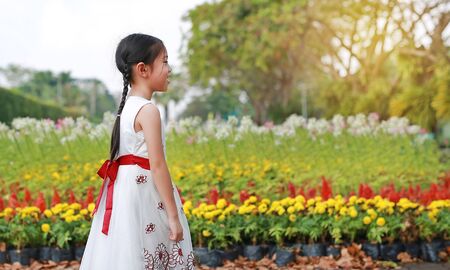 Portrait of smiling little child girl in the fresh flower gardenの写真素材