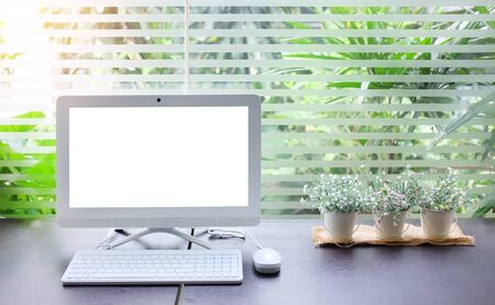desktop computer with workspace background and small bucket of artificial flowers near transparent...