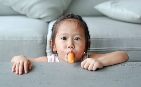 Adorable asian little kid girl enjoy eating sausage