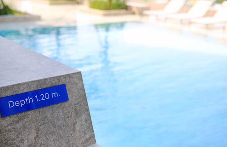 Edge of swimming pool and sign indicating the depth 1.20 meter of the pool.の写真素材