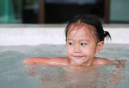 Adorable little child girl lying in the hot tub.